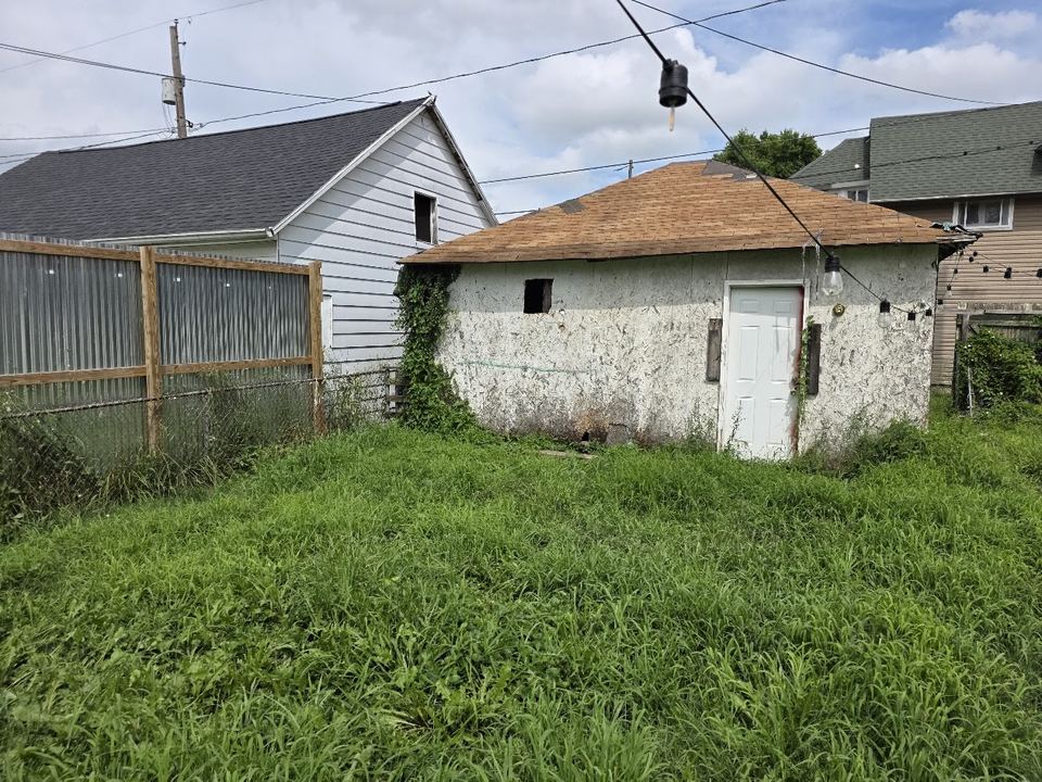 Before: Overgrown yard and a worn-out garage. Cleared out and re-sided.
